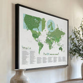 Framed world map with green continents and white oceans on a wall. 100 golf courses included