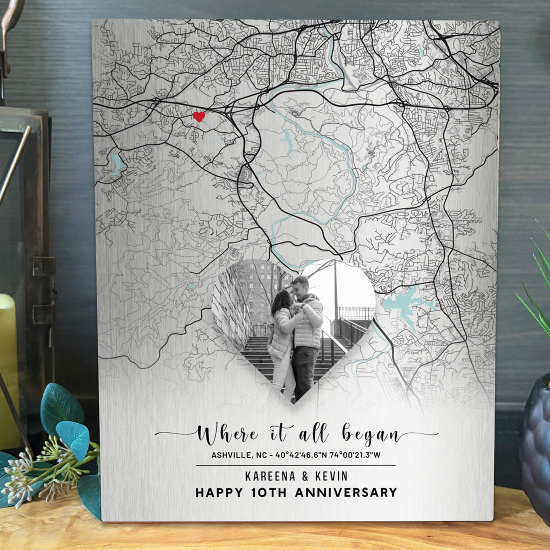 A personalized tin anniversary map canvas print featuring a black and white street map of Asheville, NC with a red heart pinpoint and a heart-shaped cutout showing a couple&