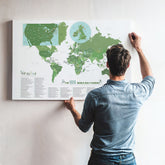 Man adjusting a world map poster on a wall